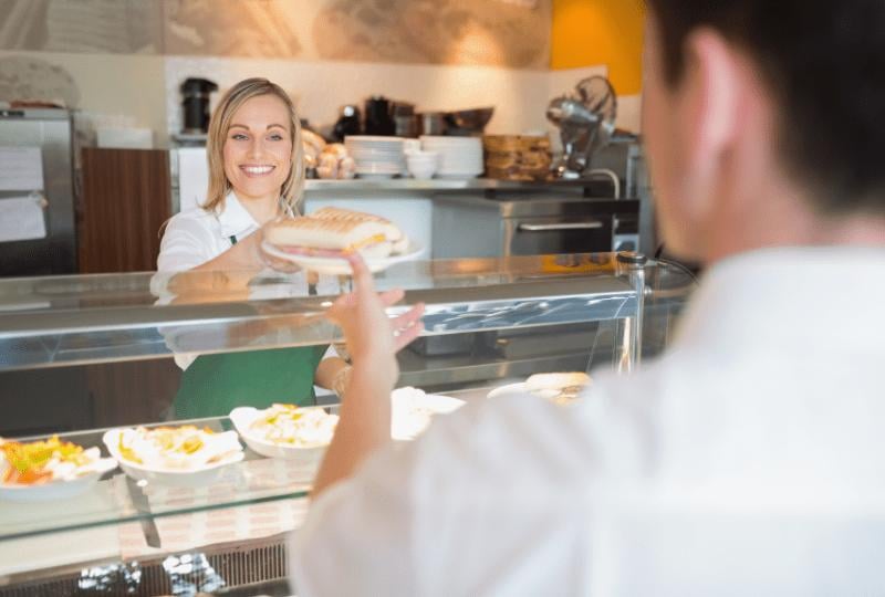 deli-store-owner-serving-fresh-sandwich