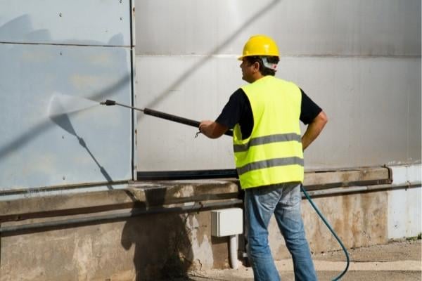 a man power washing the side of a building